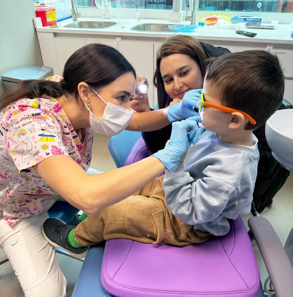 Odontopediatría → odontopediatra revisando dientes de niño pequeño